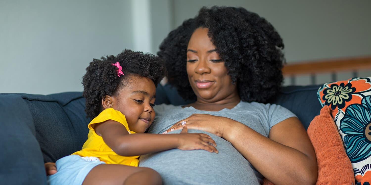 Little girl laying her hand on her pregnant mother's belly